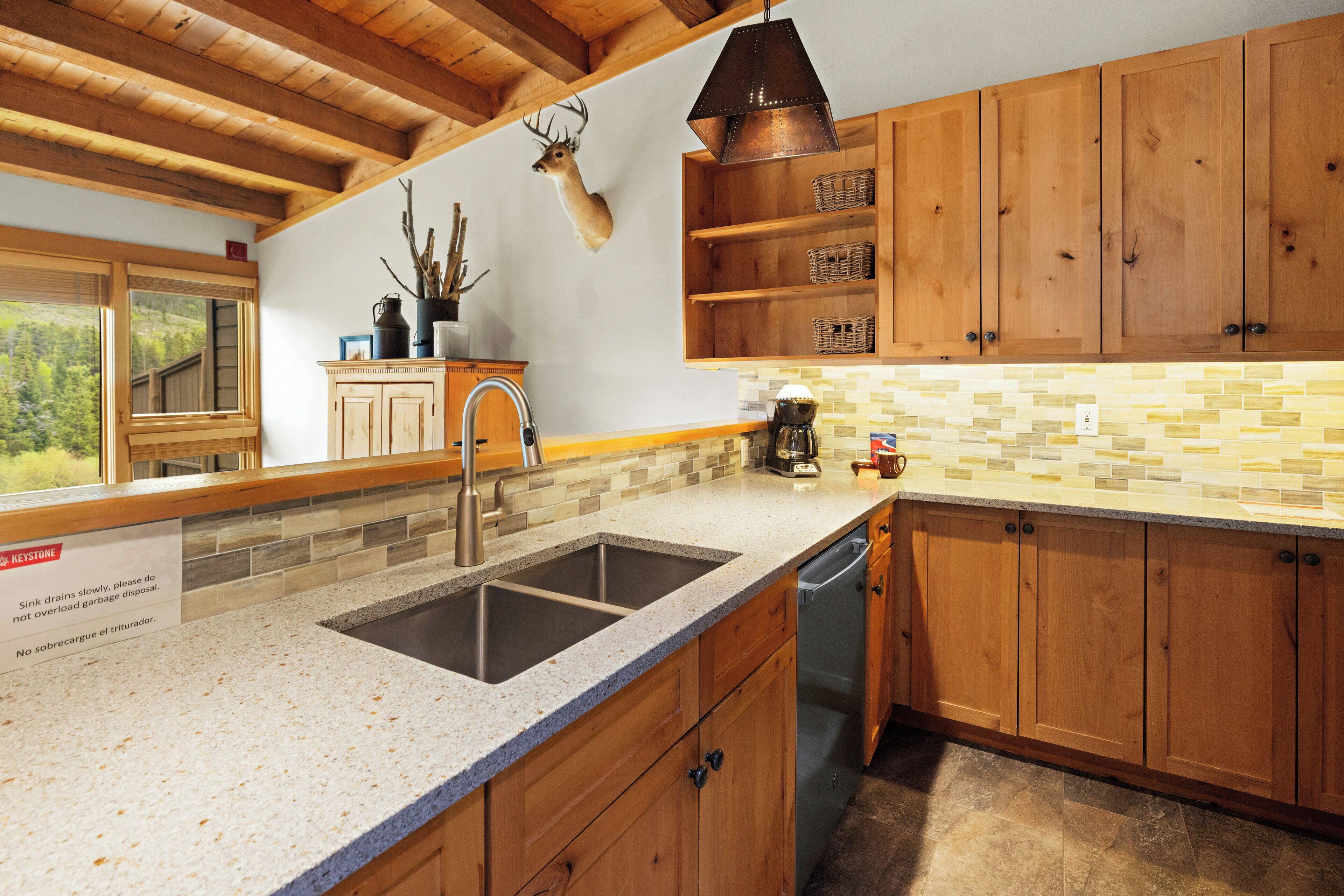 A kitchen with wooden cabinets, a granite countertop, a sink, and a dishwasher.