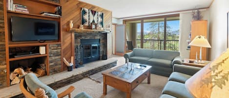 Una sala de estar con chimenea, televisor, sofá y mesa de centro.