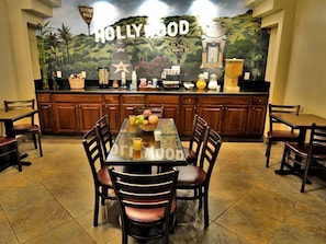 A dining area with a table, chairs, and a kitchen counter with a mural.