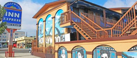 A building with a Hollywood sign, a staircase, and murals of film reels.