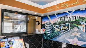 A reception area with a Hollywood-themed mural, a clock, and informational posters. - Hollywood Inn Express North (Los Angeles)