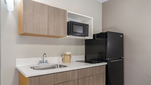 A kitchen with a microwave, refrigerator, sink, and wooden cabinets. - Baymont by Wyndham Socorro (Socorro)