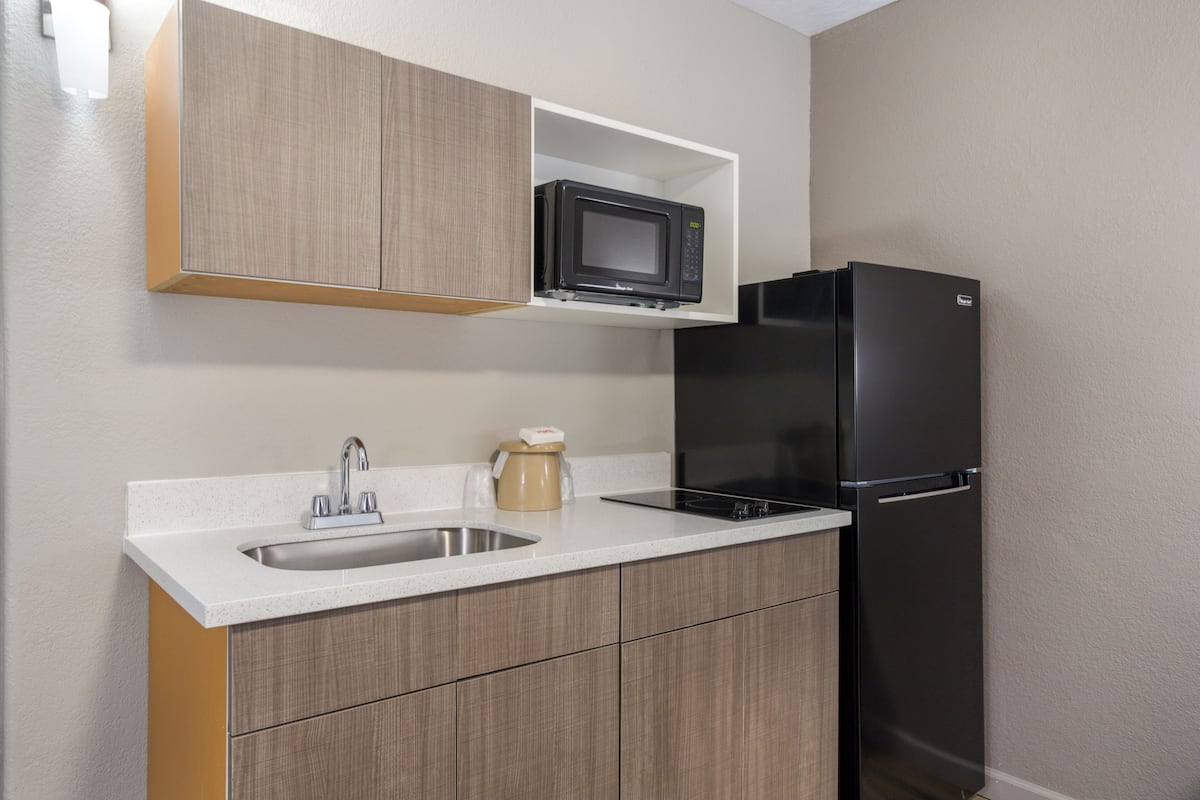 A kitchen with a microwave, refrigerator, sink, and wooden cabinets.