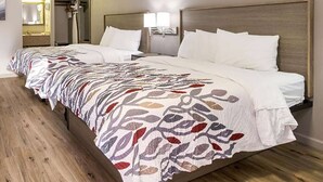 A hotel room with a large bed, a wooden floor, a bathroom with a mirror, and a nightstand with a lamp. - Baymont by Wyndham Socorro (Socorro)