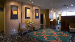 Un hall con mostrador de recepción, zona de estar y alfombra decorativa.