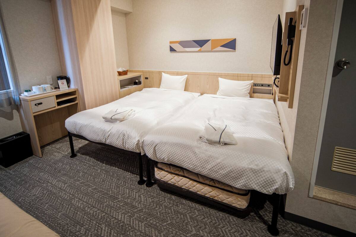 Een hotelkamer met een groot bed, nachtkastjes, een bureau en een aan de muur bevestigd telefoon.