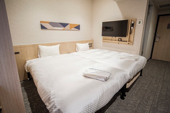 A neatly made bed with white linens, a flat-screen TV mounted on the wall, and a wooden headboard. - Hotel IL FIORE Kasai Annex (Tokyo)