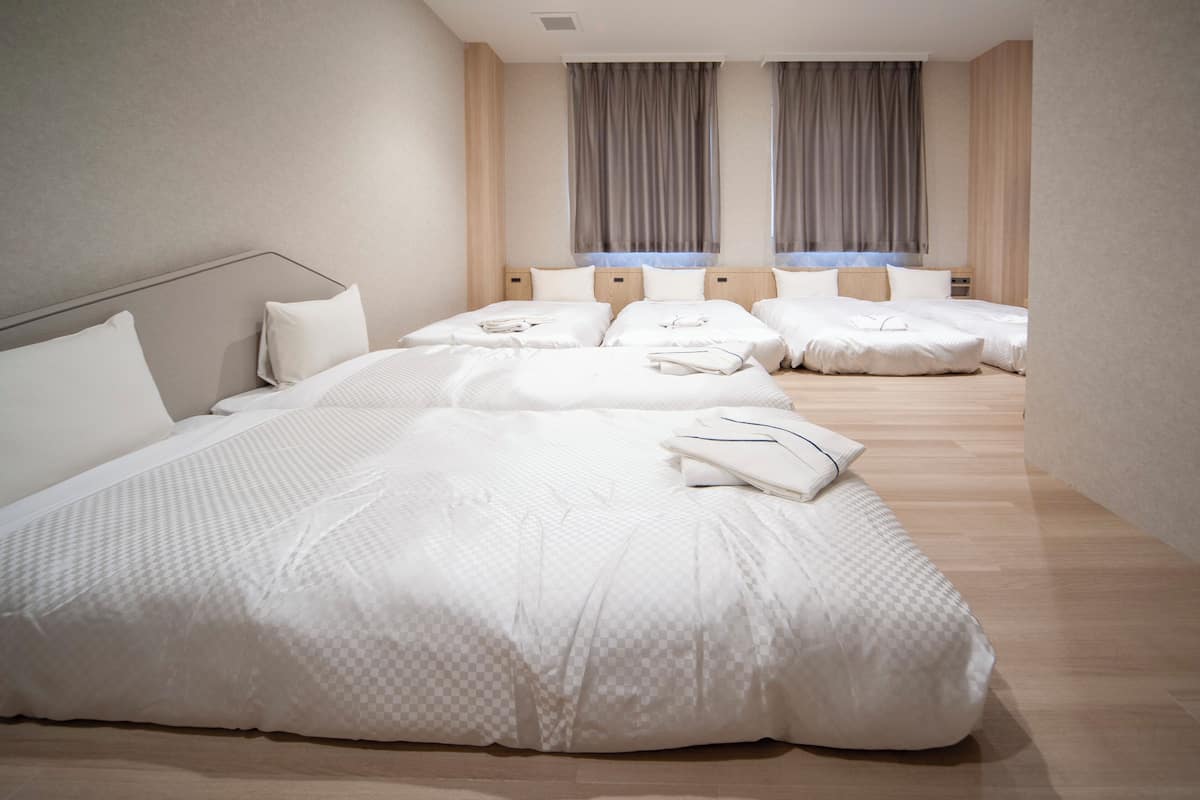 Een hotelkamer met een groot bed, twee nachtkastjes en een raam met gordijnen.