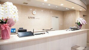 A reception desk with a clock, a computer, and a phone. - Hotel IL FIORE Kasai Annex (Tokyo)