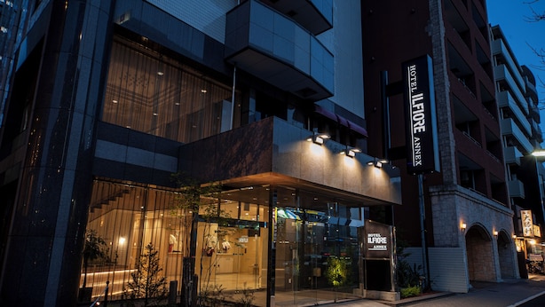 A hotel entrance with a glass facade, a visible reception desk, and a sign indicating it's the Hotel Ilforo Annex. - Hotel IL FIORE Kasai Annex (Tokyo)