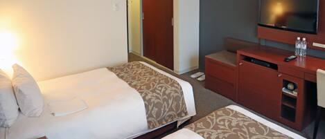 A hotel room with two beds, a TV, a desk, and a wardrobe.