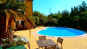 Ein Hotel mit Schwimmbad, Sitzgelegenheiten im Freien und üppigem Grün.