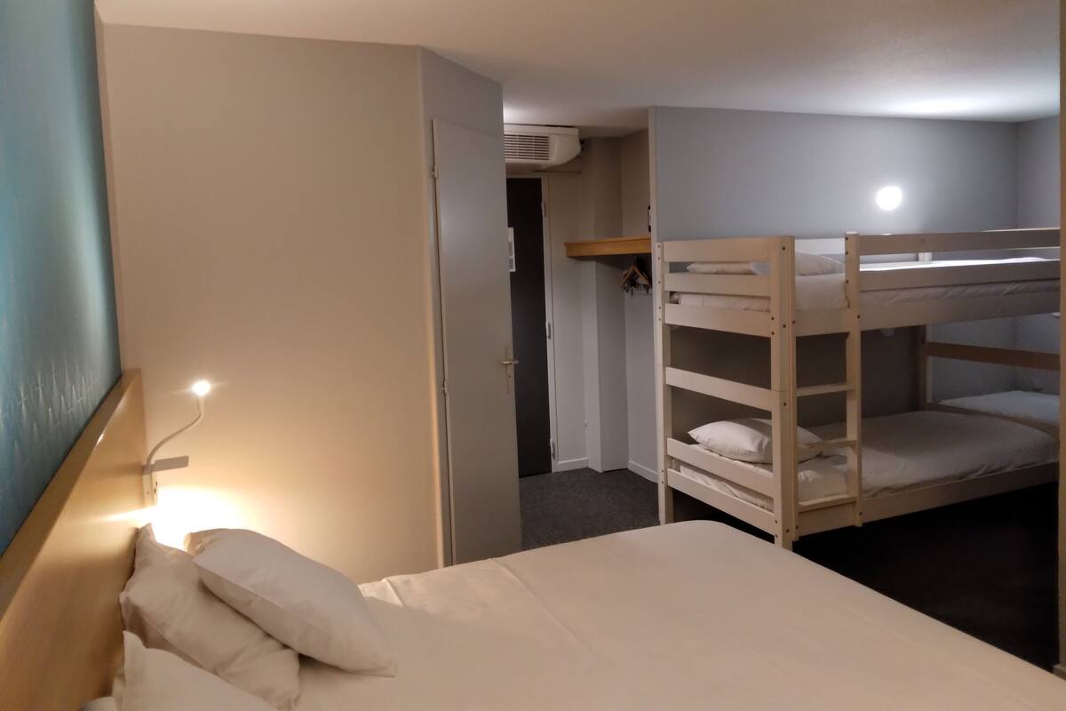 Un lit superposé avec une tête de lit, une table de chevet avec une lampe et une armoire avec un miroir.