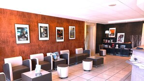 Eine Lobby mit Sitzbereichen, einem Empfangsschalter und gerahmten Filmplakaten an der Wand.