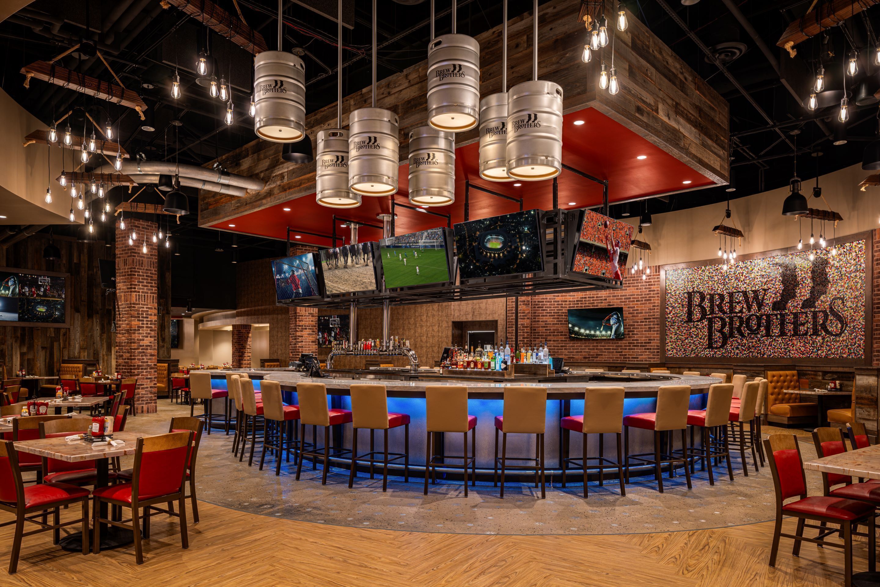 A bar area with a counter, stools, and a large screen displaying a sports event.