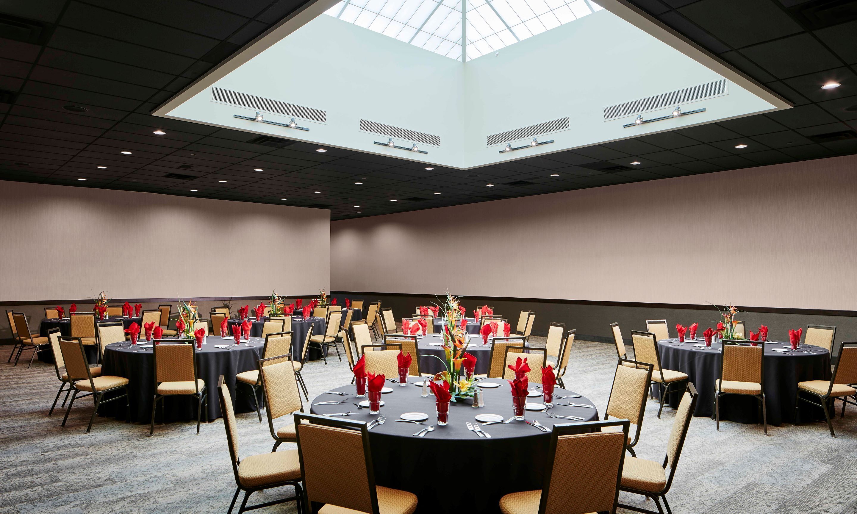 A conference room with round tables, chairs, and a large skylight.