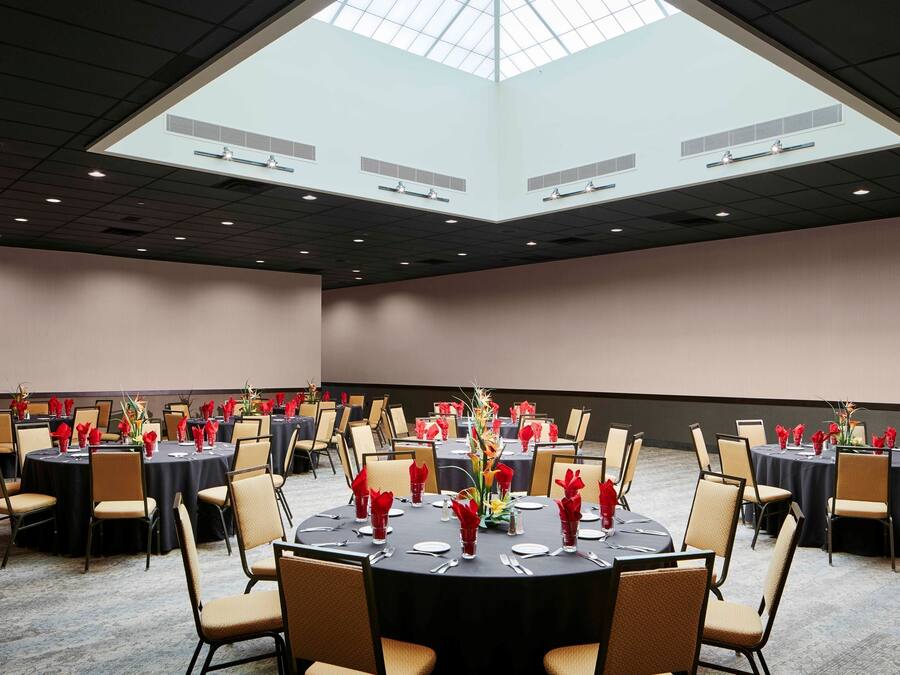 A conference room with round tables, chairs, and a large skylight.