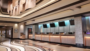 A hotel lobby with a reception desk, check-in counters, and a curved marble floor. - Harrah's Kansas City Hotel & Casino - A Caesars Rewards Destination (North Kansas City)