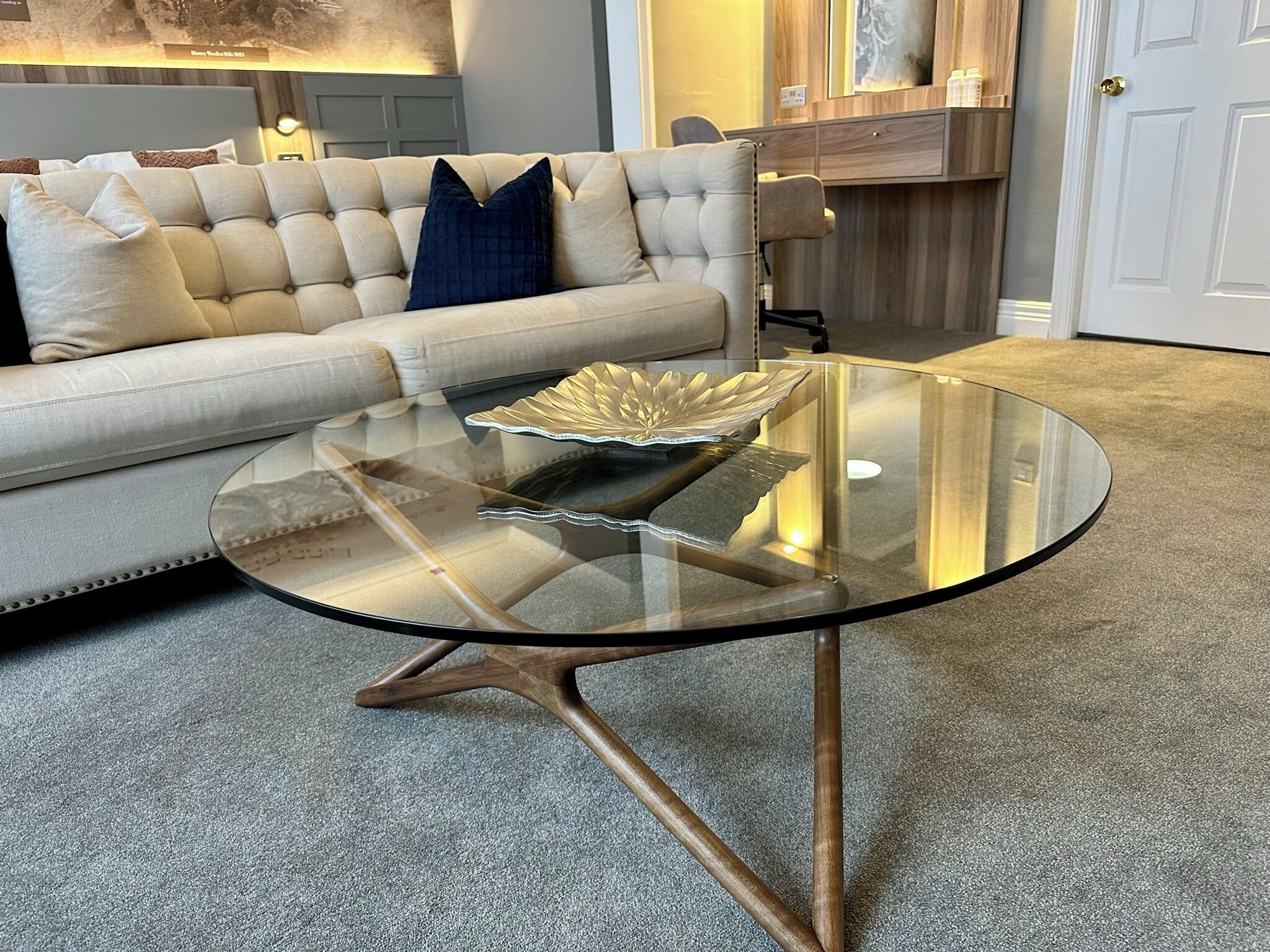 A living room with a round glass coffee table, a tufted sofa, and a decorative bowl on the table.