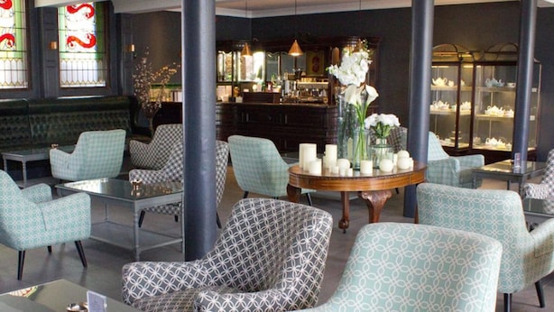 A lounge area with patterned armchairs, a round wooden table with candles, and a bar in the background. - Blarney Woollen Mills Hotel, BW Signature Collection (Blarney)