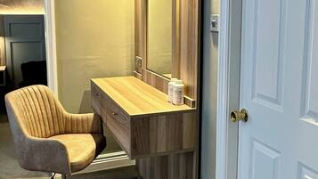 A room with a vanity area featuring a wooden vanity, a mirror, and a chair.