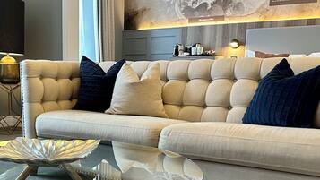 A modern living room with a tufted sofa, a glass coffee table, and a decorative metal bowl.