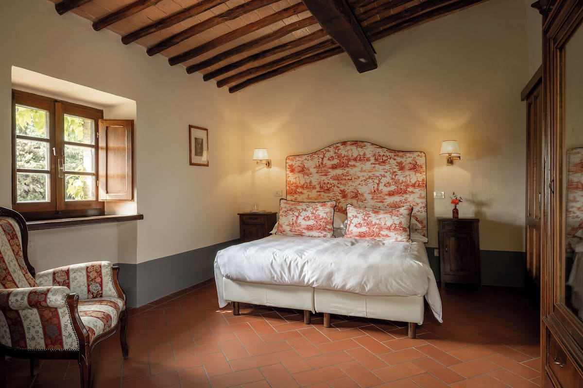 A bedroom with a bed, two bedside tables, a chair, and a window.