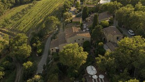 An aerial view of a villa surrounded by vineyards, with a swimming pool and outdoor seating area. - Borgo Vescine (Radda in Chianti)