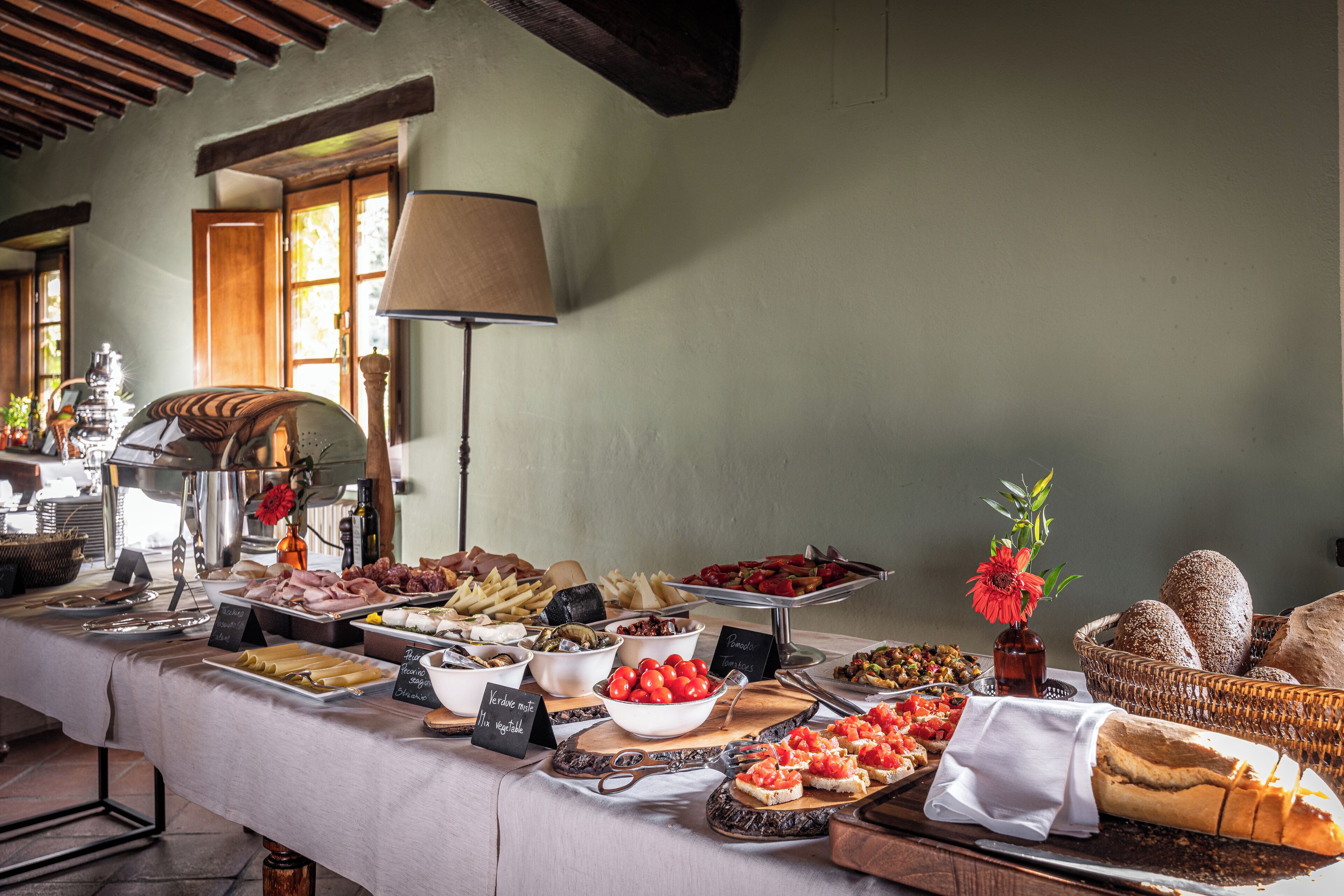 Une table de buffet garnie de divers plats, un vase avec une fleur et un panier de pain.