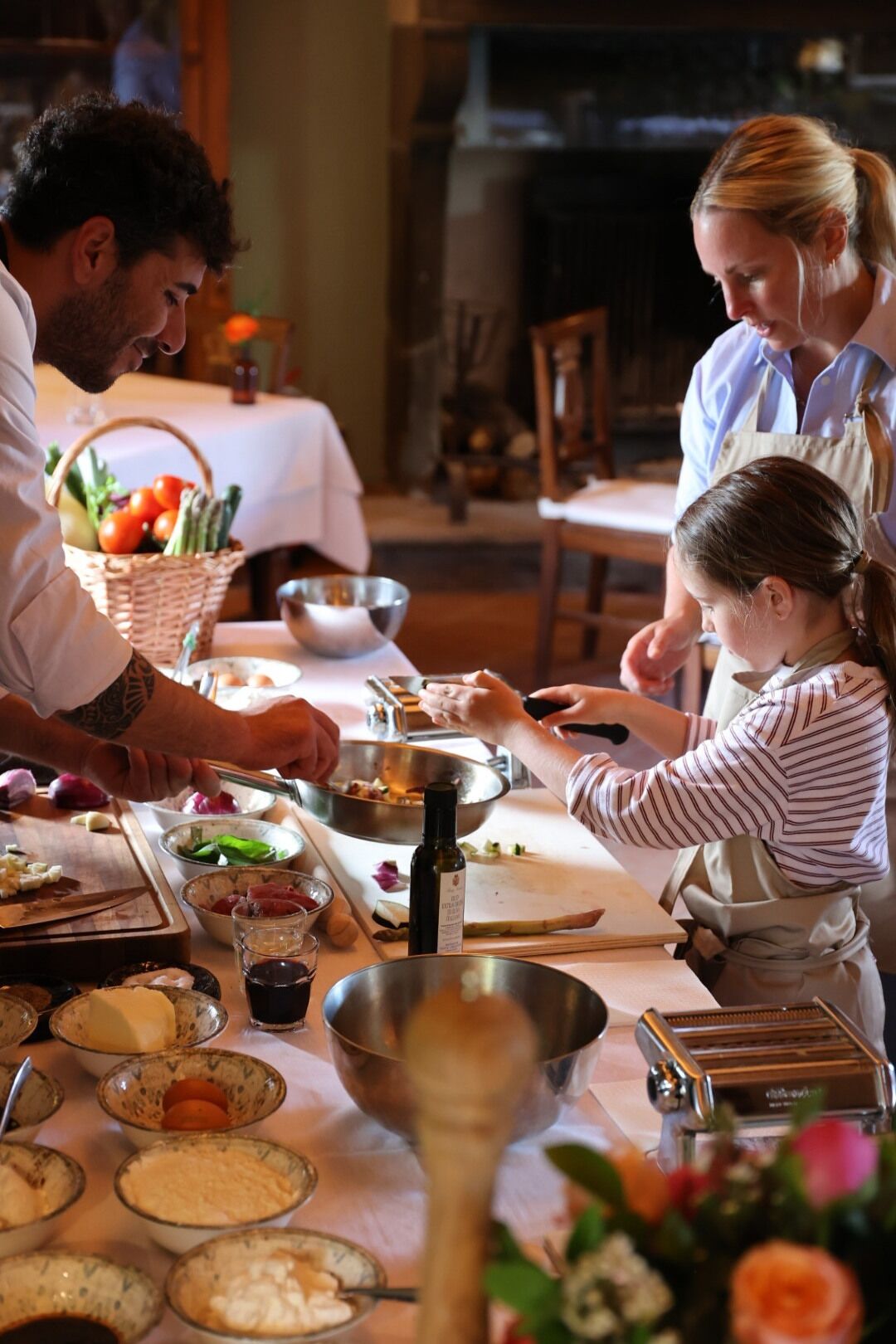 A family preparing food together in a kitchen with a dining table, various food items, and kitchen utensils.