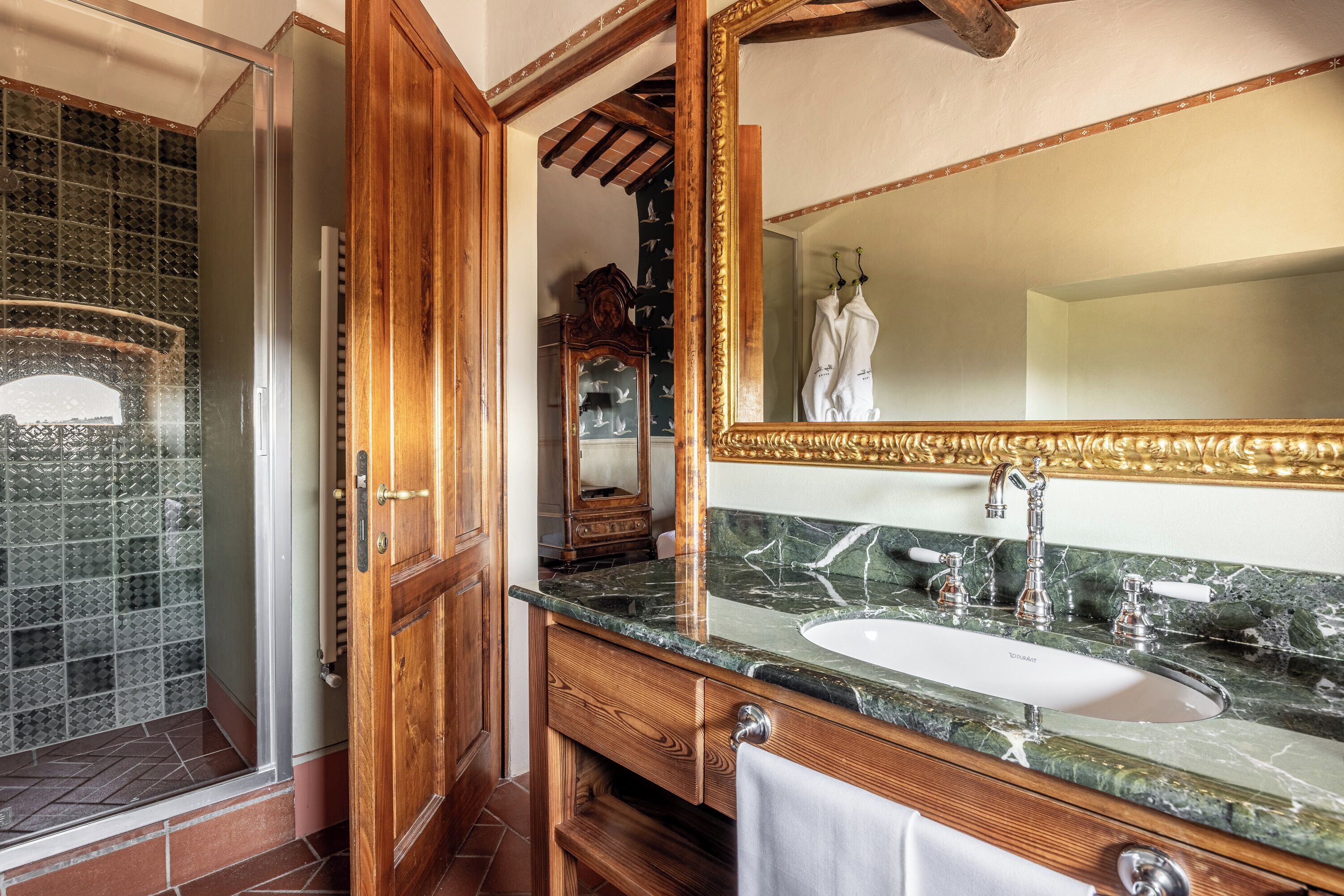 A bathroom with a wooden vanity, a large mirror, a sink, and a shower area.