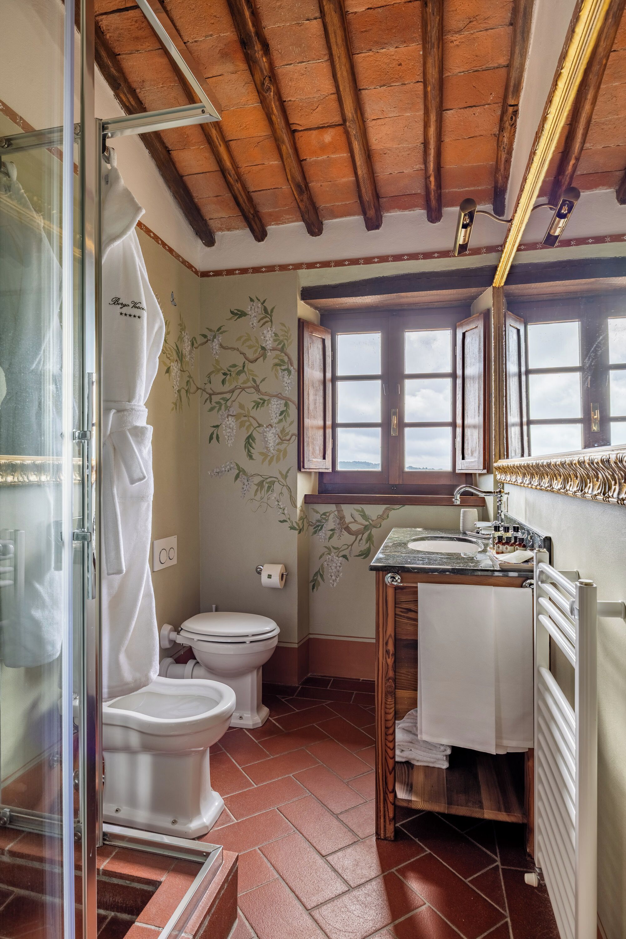 A bathroom with a wooden ceiling, a toilet, a sink, and a shower.