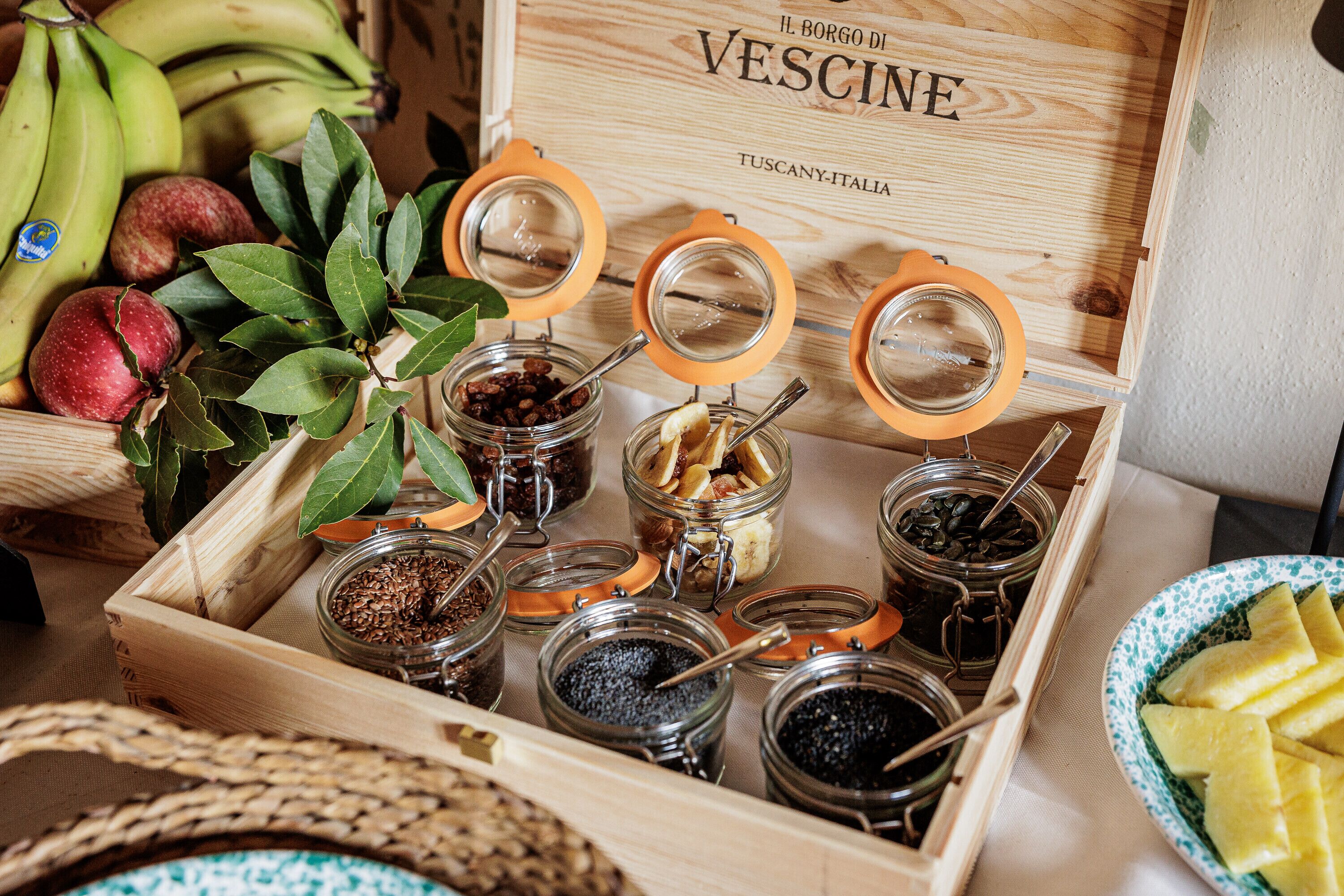 A wooden box labeled "Il Borgo di Vescine Tuscany-Italy" containing various jars of food items.