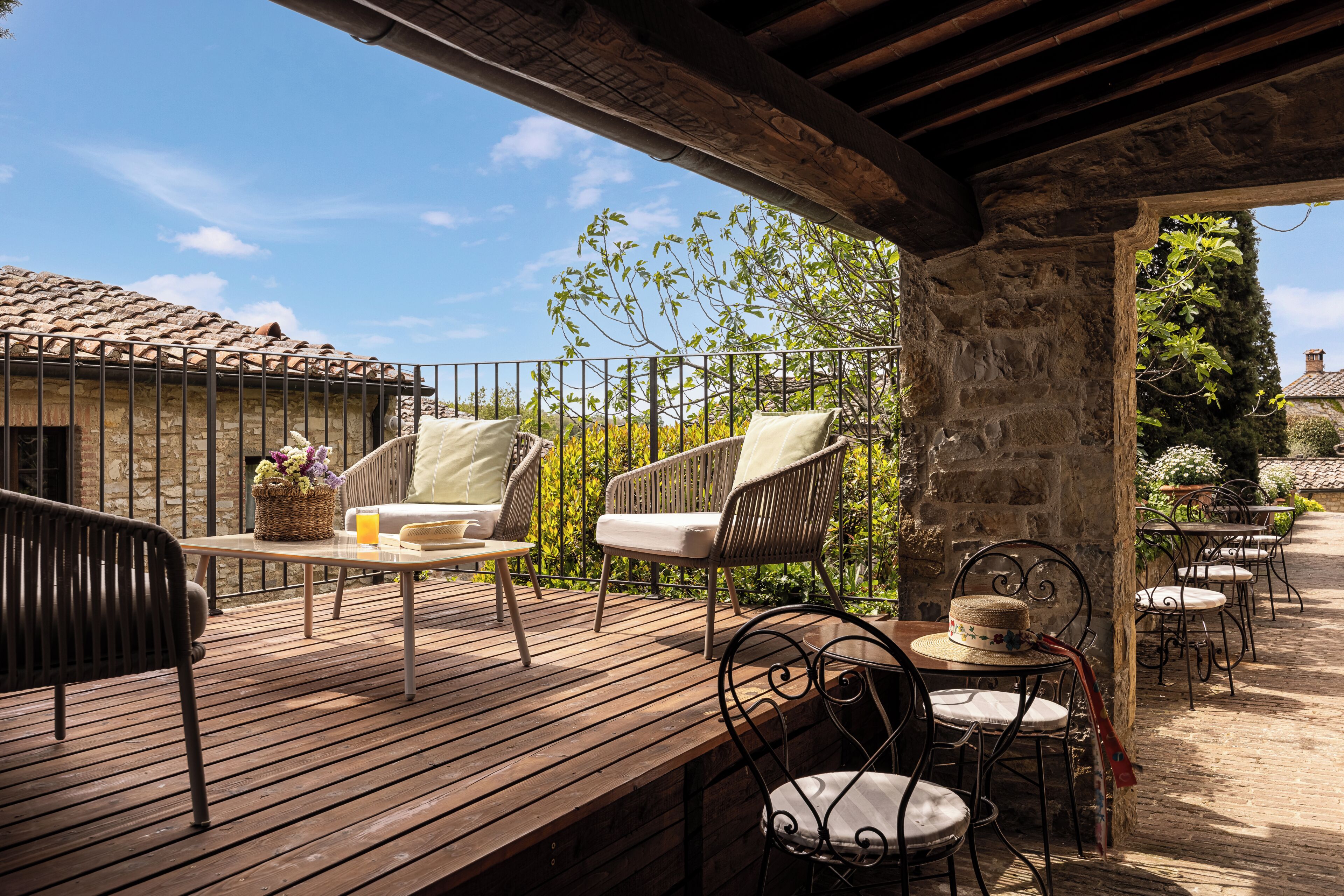 Eine Terrasse im Freien mit Korbmöbeln, einem Holztisch und einer Steinmauer.