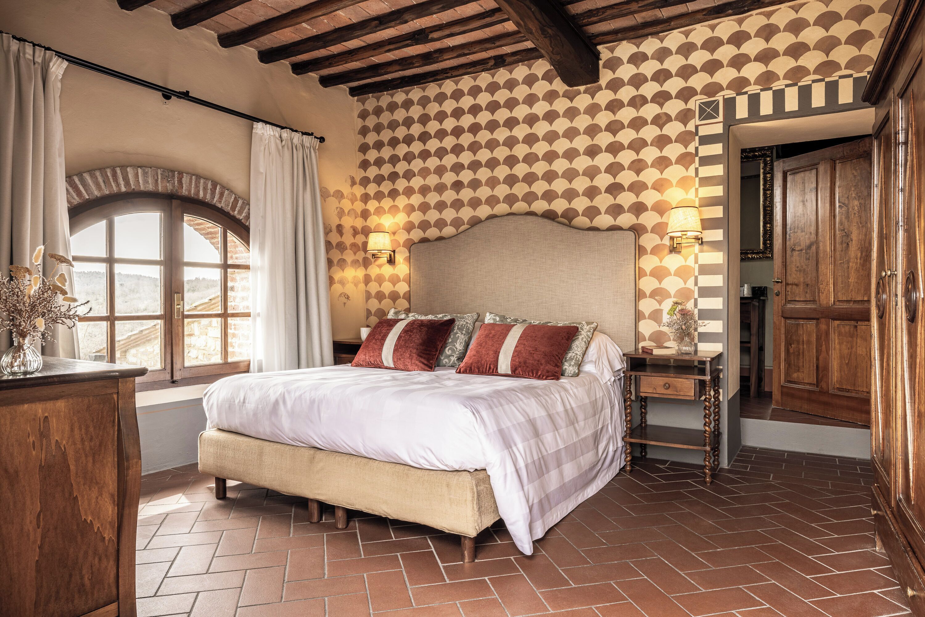 A bedroom with a bed, a nightstand, a dresser, and a window with curtains.