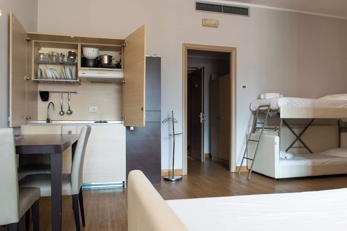 A compact room with a bed, a desk, and a kitchenette.