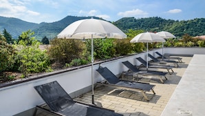 A rooftop terrace with sun loungers and umbrellas, overlooking a mountainous landscape. - Regal Hotel (Brescia)
