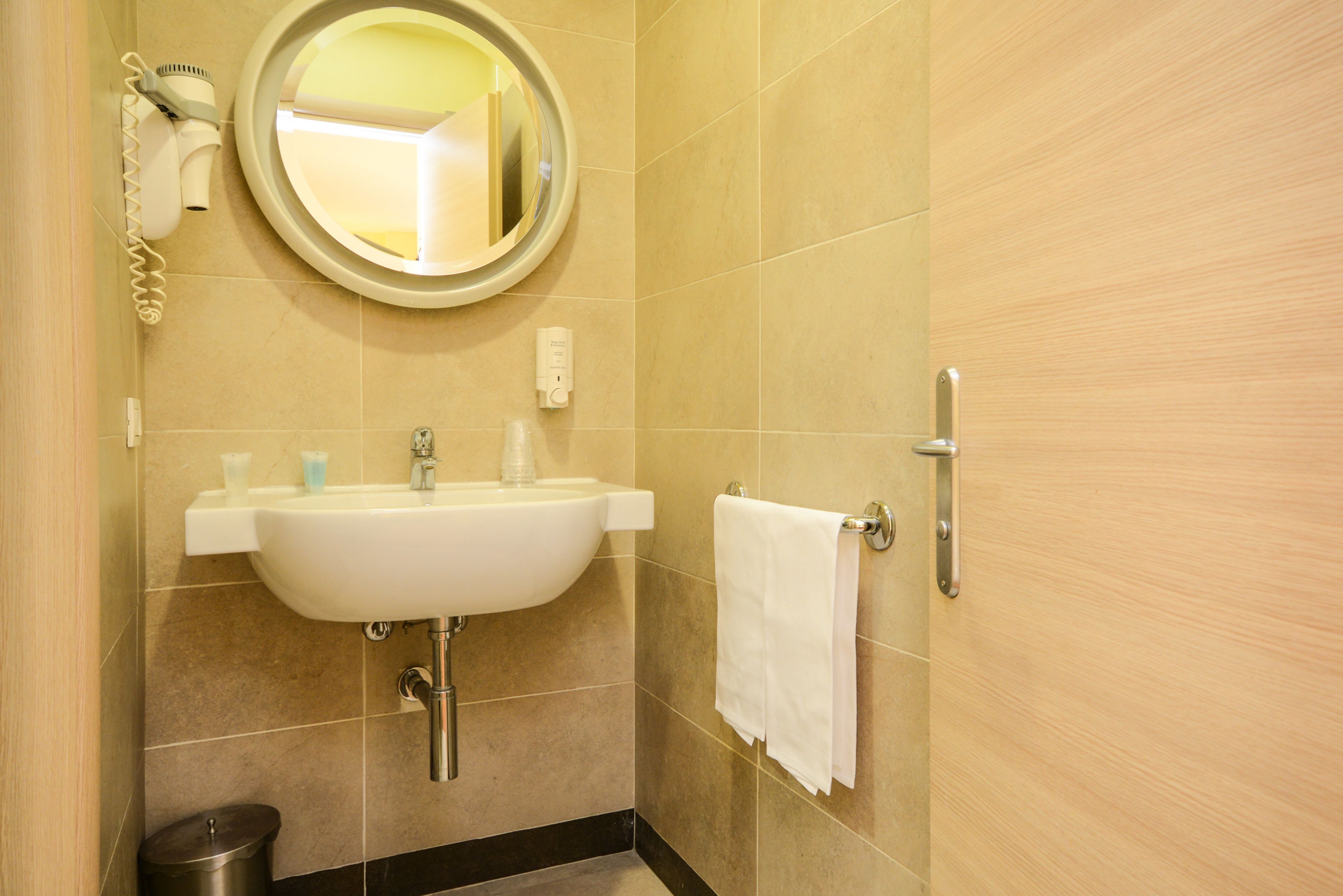 A bathroom with a sink, mirror, towel rack, and a trash bin.