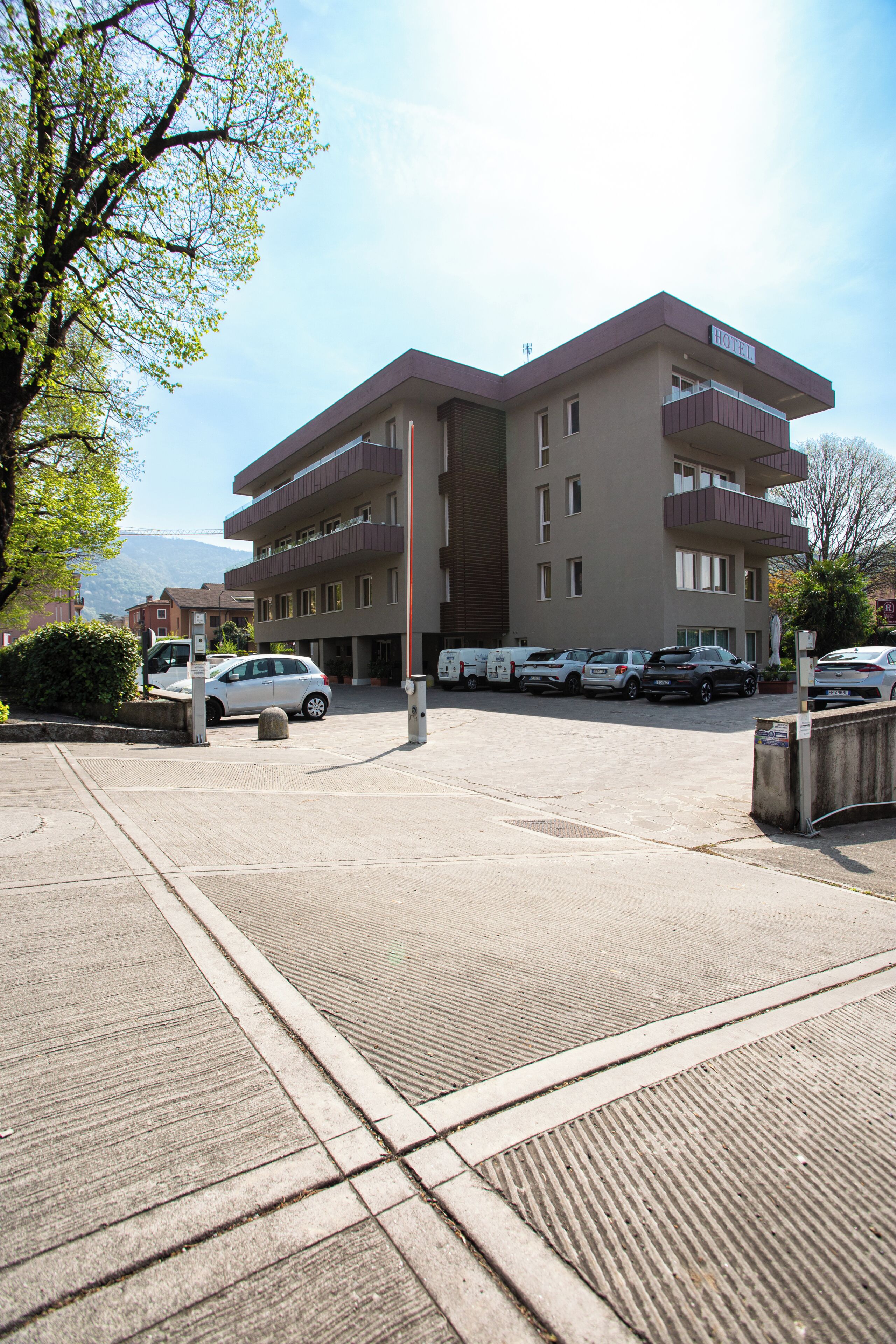 A multi-story hotel with a parking lot, several cars, and a clear sky.
