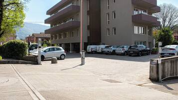 A multi-story hotel with a parking lot, several cars, and a clear sky.