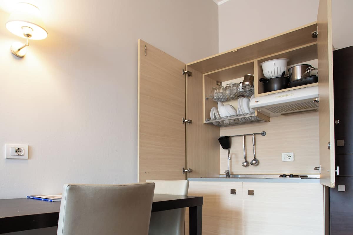A compact kitchen with a dining area, featuring a built-in oven, a sink, and a countertop with dishes.