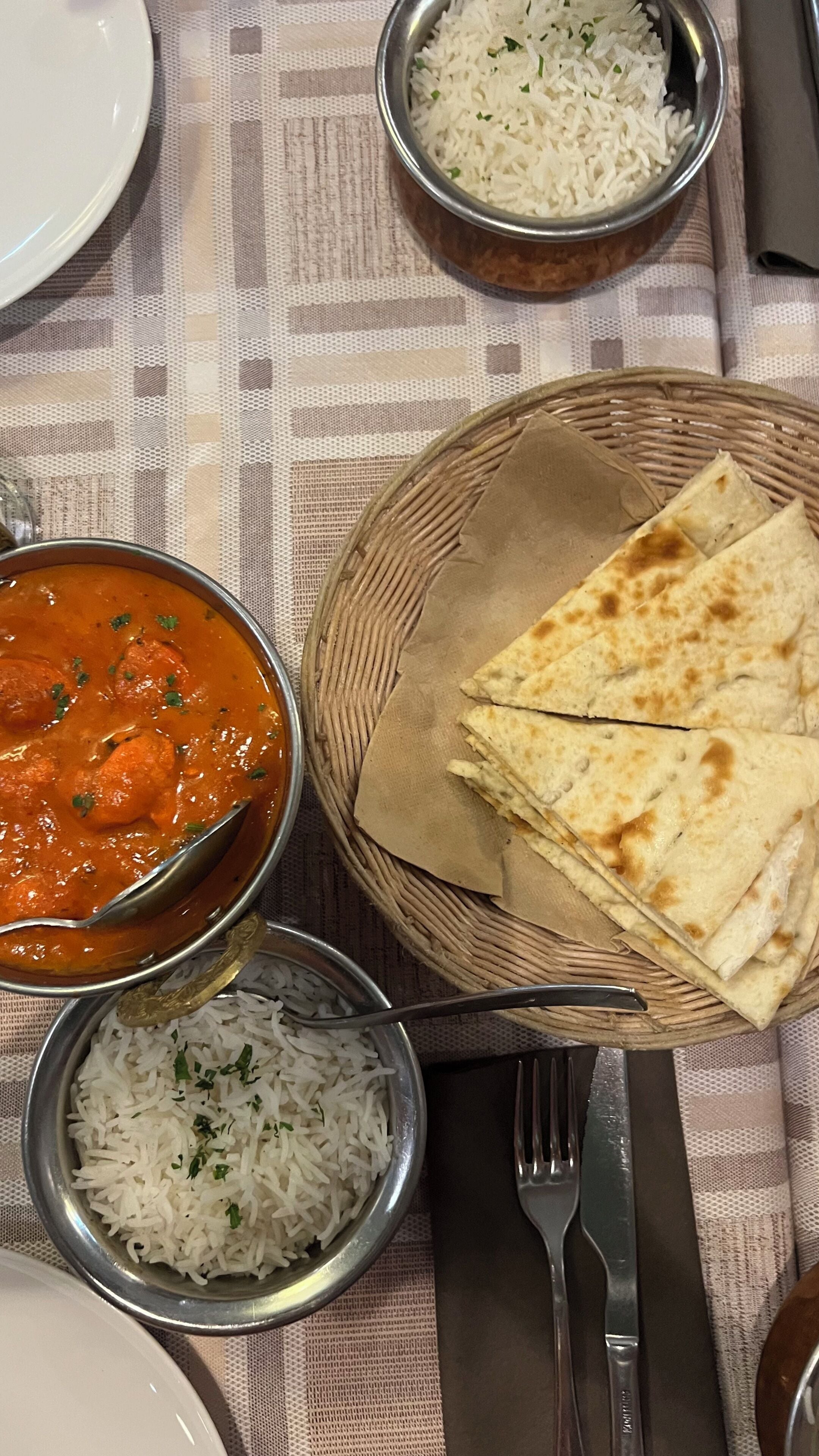 Een tafel met naanbrood, een portie rijst en een kom curry.