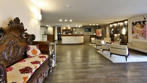 A hotel lobby with a wooden sofa, a reception desk, and a bar area. - Regal Hotel (Brescia)