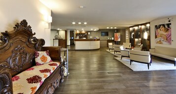 Un hall d’hôtel avec un canapé en bois, un comptoir d’accueil et un espace bar.