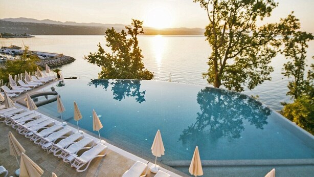 An infinity pool with lounge chairs and umbrellas, overlooking a body of water and mountains. - Grand Hotel Adriatic I (Opatija)