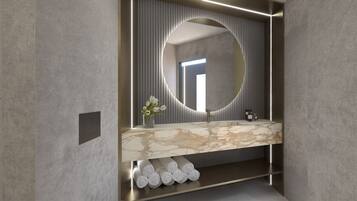 Un baño moderno con tocador de mármol, un espejo redondo grande y un perchero con toallas enrolladas ordenadamente.