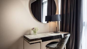 Un bureau d’hôtel moderne avec un plateau en marbre, une lampe noire, un vase avec des fleurs et une chaise.