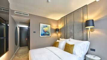 Habitación de hotel con cama, mesita de noche, lámpara de pared y un cuadro.