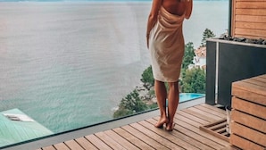 A woman standing on a wooden deck overlooking a body of water with a view of distant land and trees. - Grand Hotel Adriatic I (Opatija)