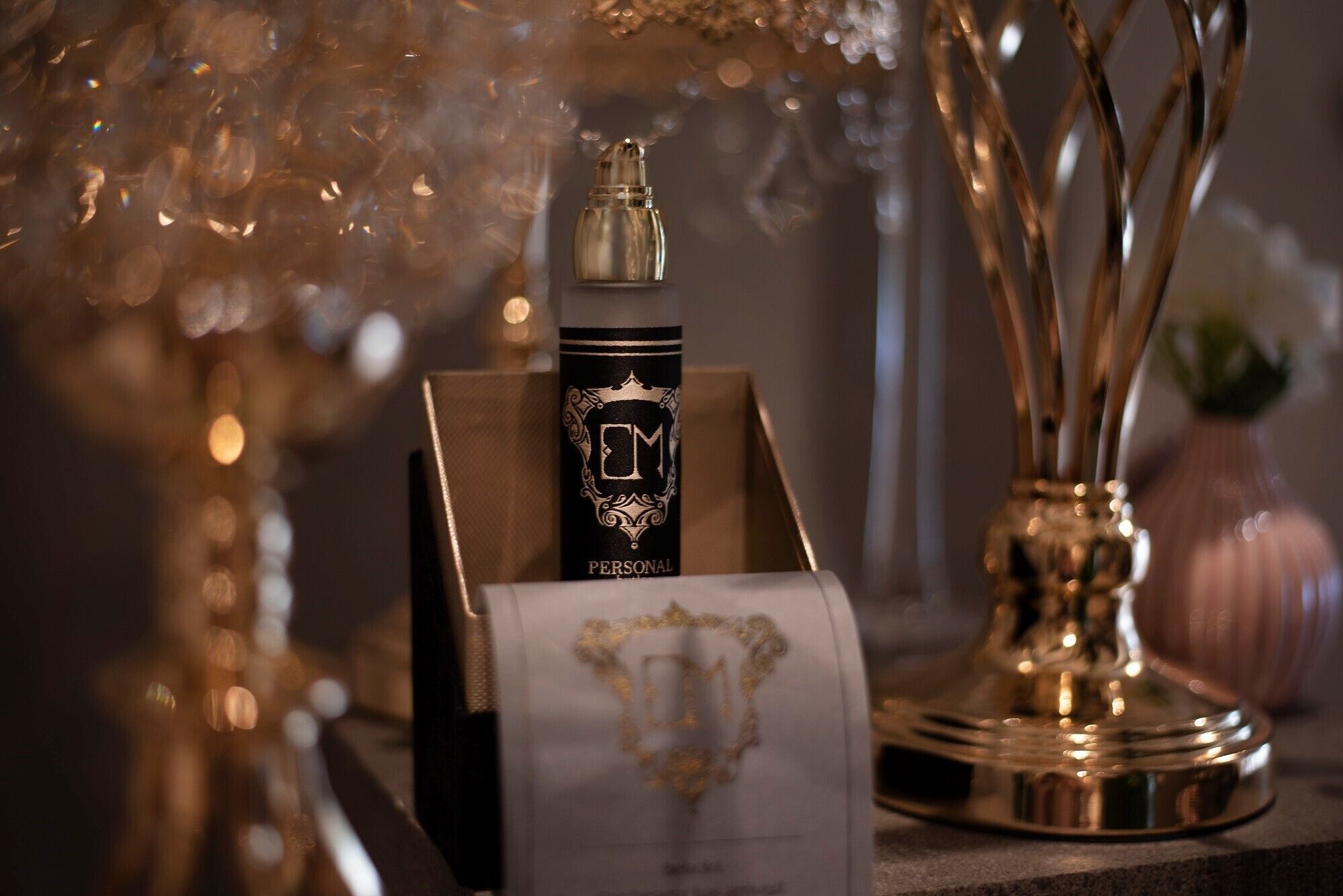 A personal care product display with a bottle and box, a decorative lamp, and a vase with branches.